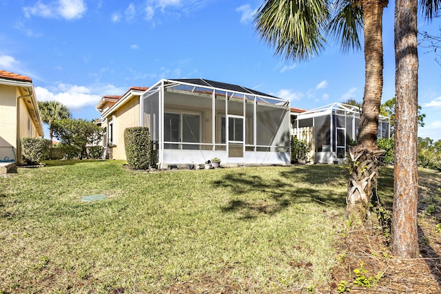 back of property with a lanai, a tile roof, a yard, and stucco siding