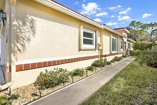 view of side of home with a yard and stucco siding