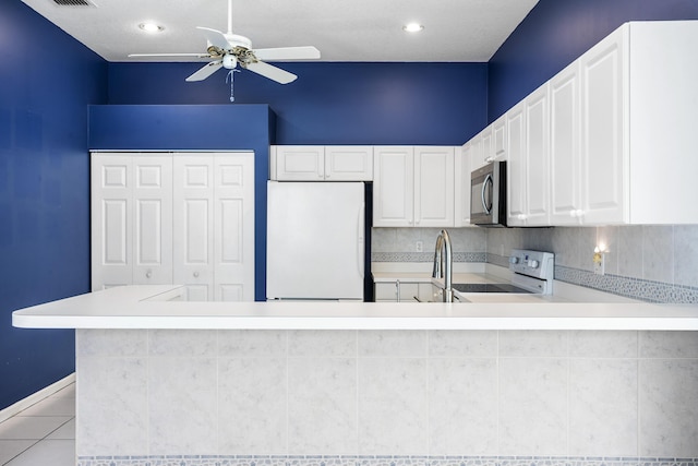 kitchen featuring electric stove, light countertops, stainless steel microwave, freestanding refrigerator, and white cabinetry