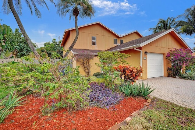 view of front of house with a garage, roof with shingles, decorative driveway, and stucco siding