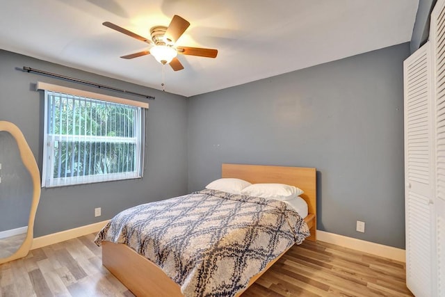 bedroom featuring ceiling fan, a closet, baseboards, and wood finished floors