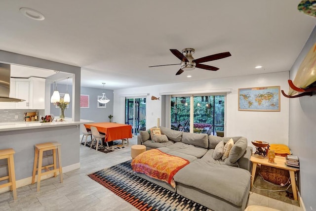 living room with recessed lighting, baseboards, and ceiling fan with notable chandelier