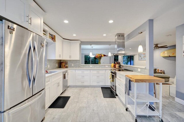 kitchen with decorative light fixtures, island range hood, kitchen peninsula, and a breakfast bar area