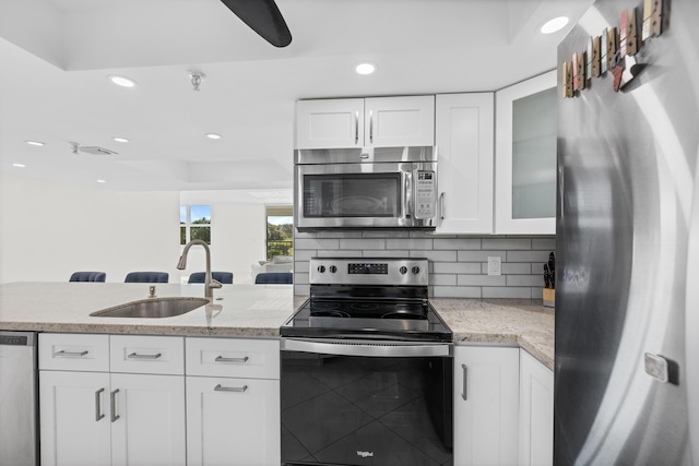 kitchen featuring white cabinetry, sink, light stone countertops, backsplash, and appliances with stainless steel finishes