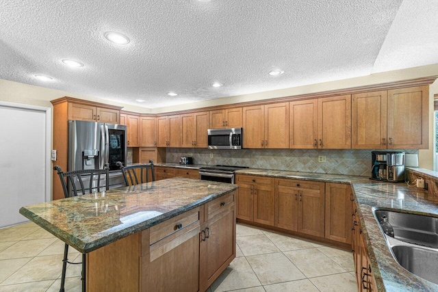 kitchen with sink, a center island, a breakfast bar area, light tile patterned flooring, and appliances with stainless steel finishes