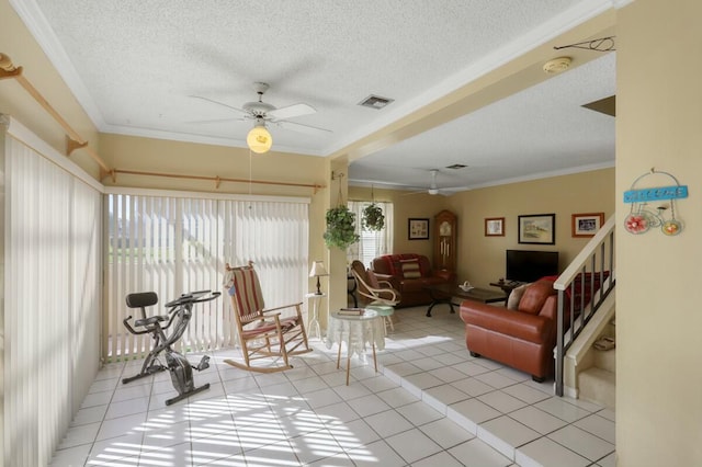 living room featuring ceiling fan, light tile patterned flooring, ornamental molding, and a textured ceiling