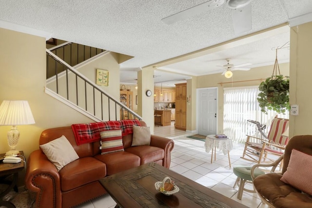 living room with a textured ceiling, ceiling fan, and light tile patterned flooring