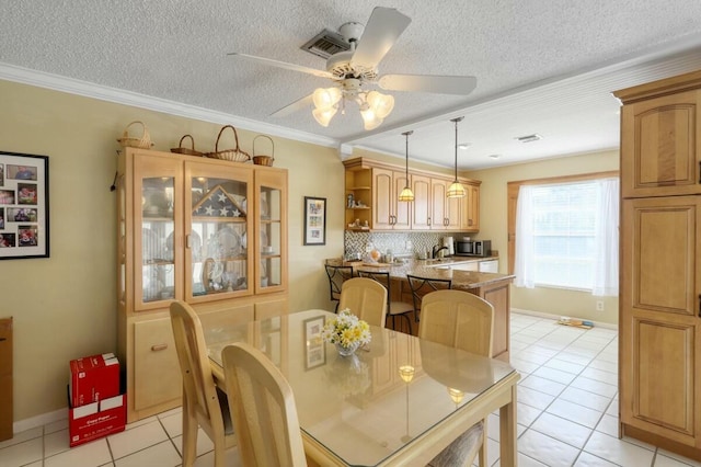 tiled dining room with a textured ceiling, ceiling fan, and crown molding