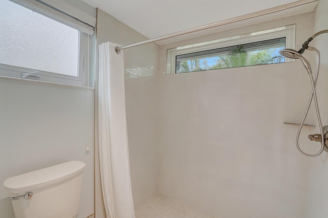 full bathroom featuring a tile shower and toilet