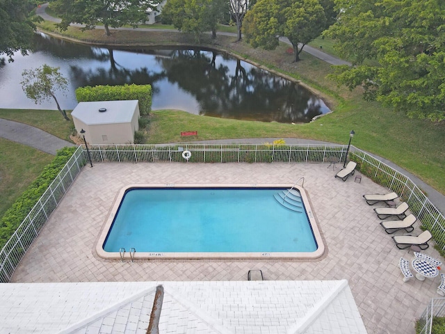 pool featuring a yard, a water view, fence, and a patio