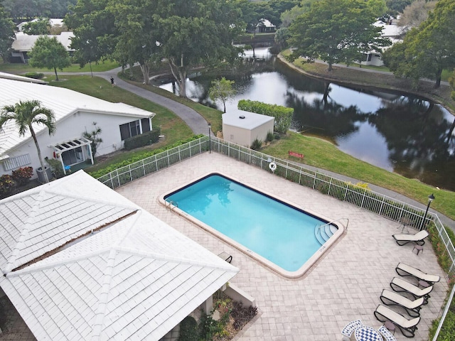 pool featuring a yard, a water view, fence, and a patio