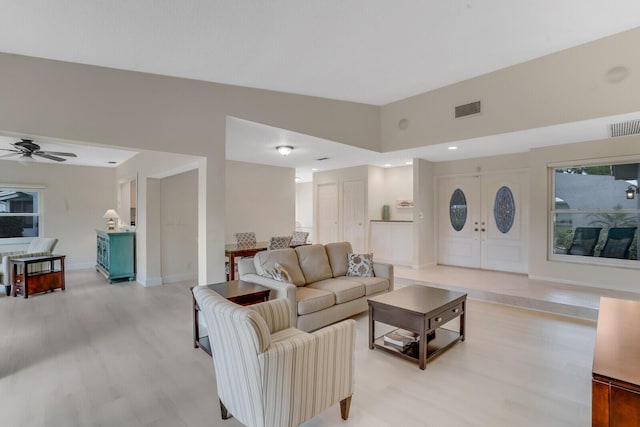 living area with lofted ceiling, ceiling fan, light wood-style flooring, visible vents, and baseboards