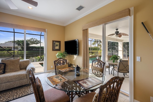 tiled dining room featuring ceiling fan and crown molding