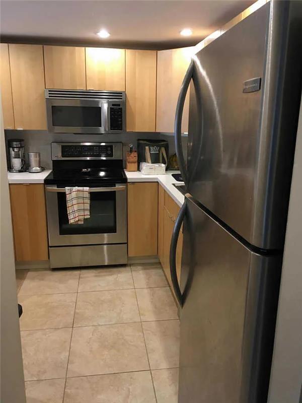 kitchen with light brown cabinetry, light tile patterned floors, and stainless steel appliances