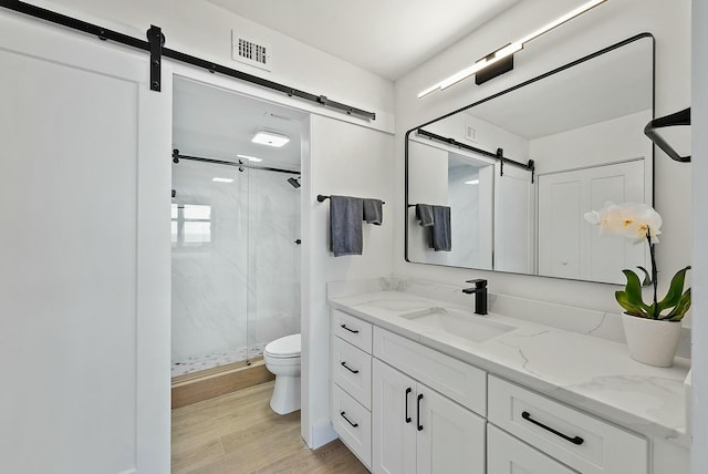 bathroom featuring hardwood / wood-style flooring, toilet, vanity, and walk in shower