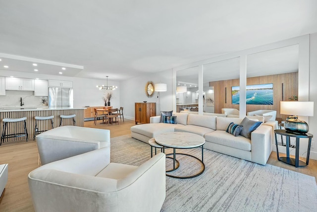 living room featuring sink, a chandelier, and light hardwood / wood-style floors