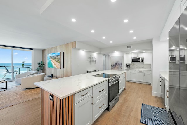 kitchen featuring floor to ceiling windows, a water view, white cabinetry, and stainless steel appliances