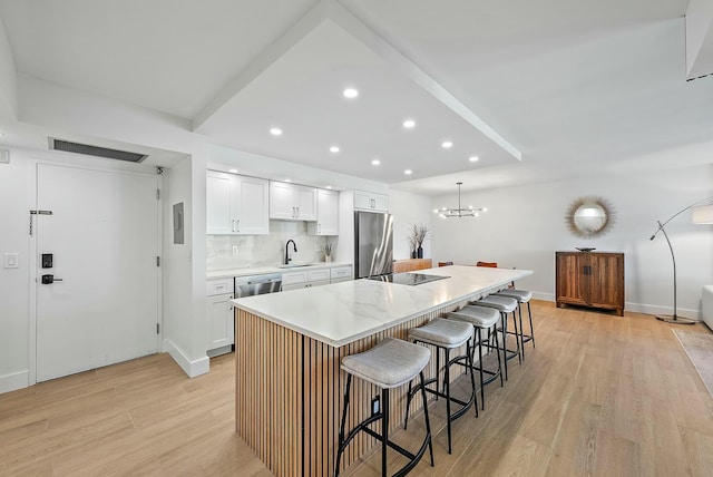 kitchen featuring white cabinets, sink, a breakfast bar area, a kitchen island, and stainless steel appliances