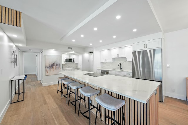 kitchen featuring a kitchen breakfast bar, a large island, white cabinets, and appliances with stainless steel finishes