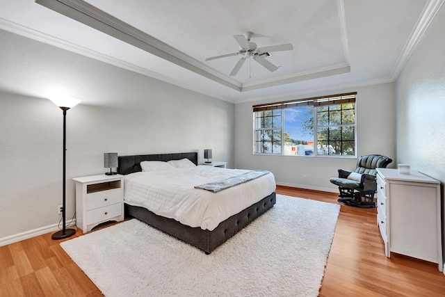 bedroom with ceiling fan, light hardwood / wood-style floors, ornamental molding, and a tray ceiling