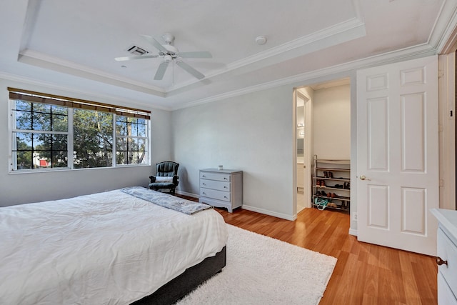 bedroom featuring a raised ceiling, ceiling fan, light hardwood / wood-style flooring, and crown molding