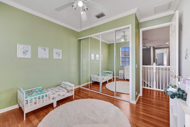 bedroom featuring hardwood / wood-style floors, a closet, ceiling fan, and ornamental molding