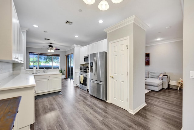 kitchen featuring crown molding, hardwood / wood-style flooring, ceiling fan, white cabinetry, and stainless steel appliances