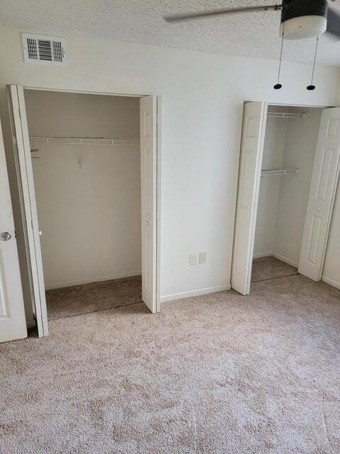 unfurnished bedroom with light carpet, a textured ceiling, and ceiling fan