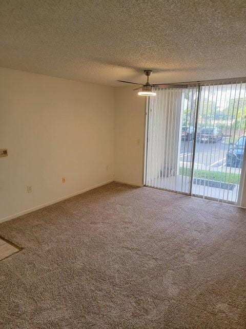 carpeted spare room with ceiling fan and a textured ceiling