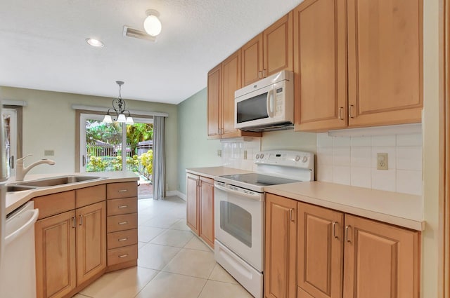 kitchen featuring pendant lighting, white appliances, sink, light tile patterned flooring, and a chandelier