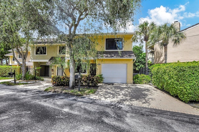 view of front facade with decorative driveway, an attached garage, and stucco siding