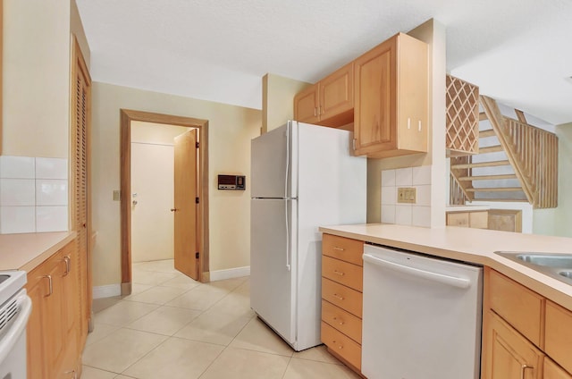 kitchen with light brown cabinetry, tasteful backsplash, white appliances, a textured ceiling, and light tile patterned floors