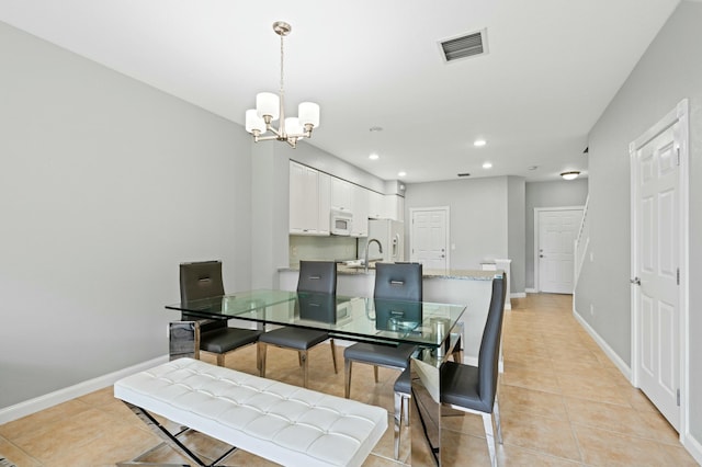 dining area with sink, light tile patterned floors, and a chandelier