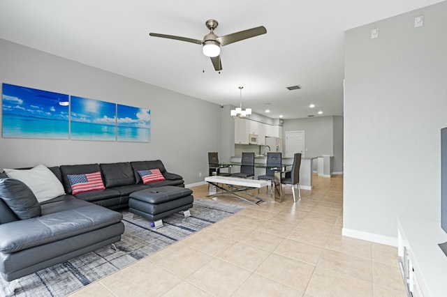 tiled living room featuring ceiling fan with notable chandelier and sink