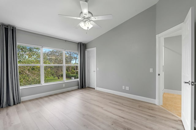 empty room featuring ceiling fan, vaulted ceiling, and light wood-type flooring