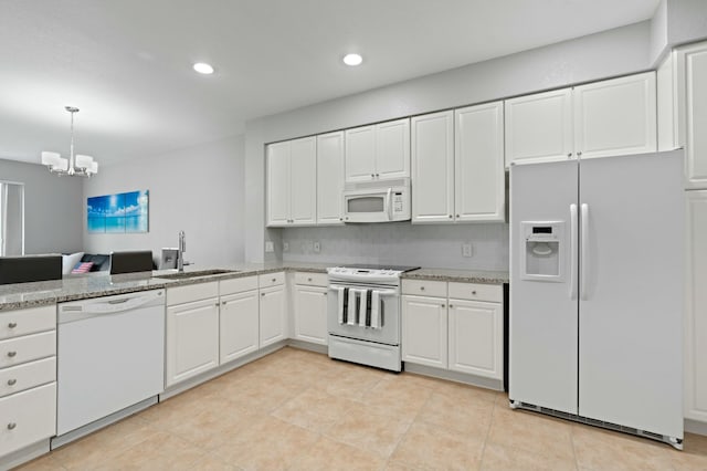 kitchen with white appliances, white cabinets, sink, light stone counters, and a chandelier