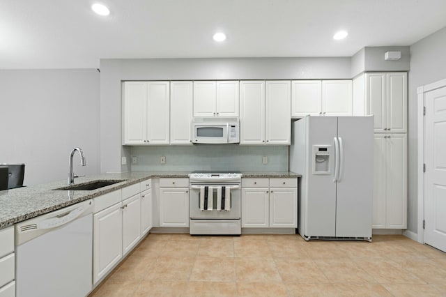 kitchen featuring decorative backsplash, light stone counters, white appliances, sink, and white cabinets