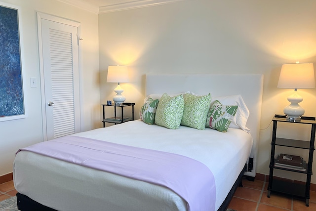 bedroom with tile patterned flooring, a closet, and crown molding