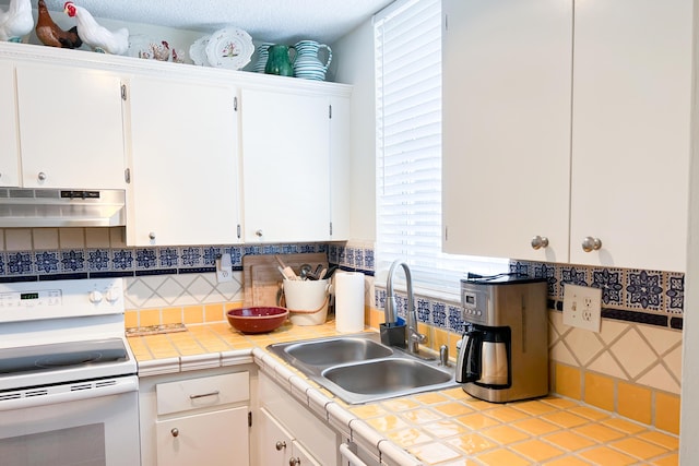 kitchen with tile countertops, stove, and white cabinetry