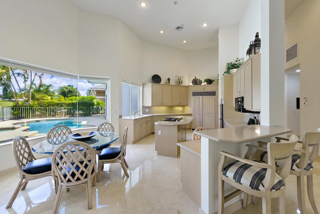 kitchen featuring sink, a high ceiling, a kitchen bar, paneled built in fridge, and a kitchen island