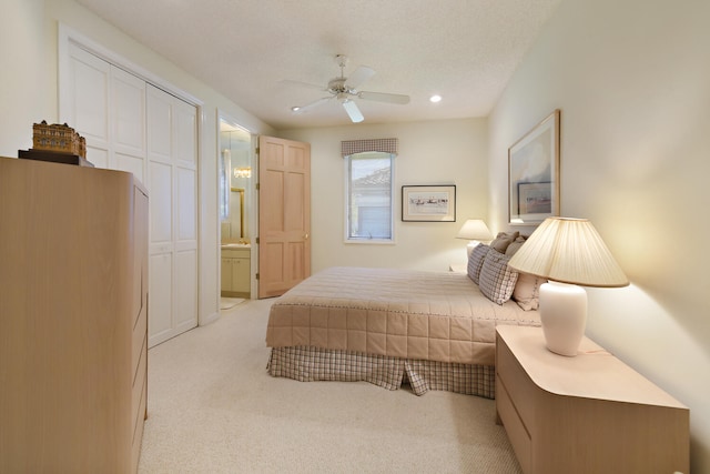 bedroom featuring connected bathroom, ceiling fan, a closet, and light carpet