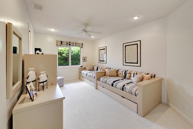 living room featuring ceiling fan, light colored carpet, and a textured ceiling