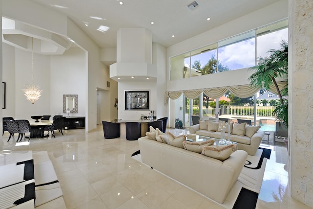 living room featuring a wealth of natural light, a towering ceiling, and a notable chandelier