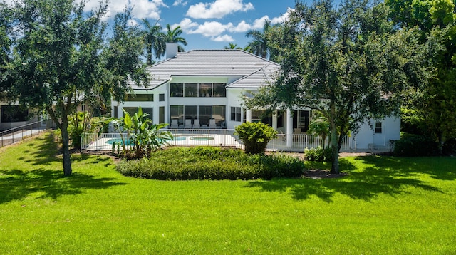 rear view of house with a fenced in pool and a yard