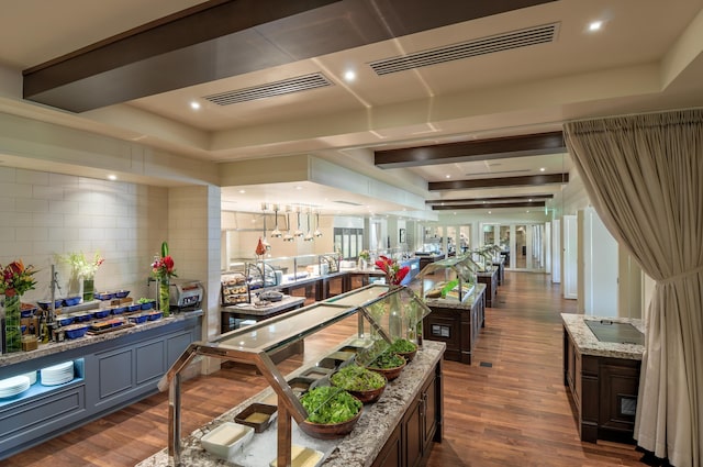 interior space with dark hardwood / wood-style floors, light stone countertops, a tray ceiling, tasteful backsplash, and dark brown cabinetry