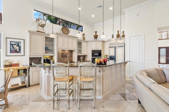 kitchen with a kitchen island with sink, hanging light fixtures, paneled refrigerator, cream cabinets, and backsplash