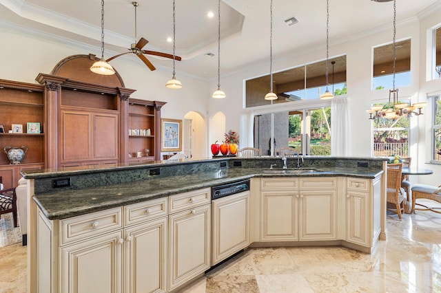 kitchen featuring dark stone counters, hanging light fixtures, cream cabinets, and a tray ceiling