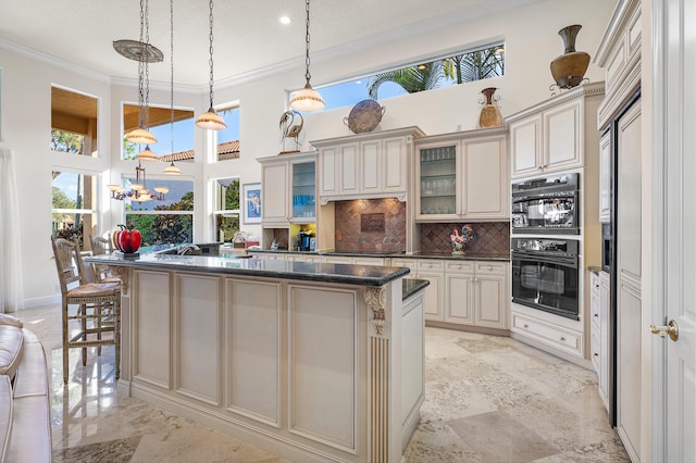 kitchen with ornamental molding, pendant lighting, cream cabinets, and decorative backsplash