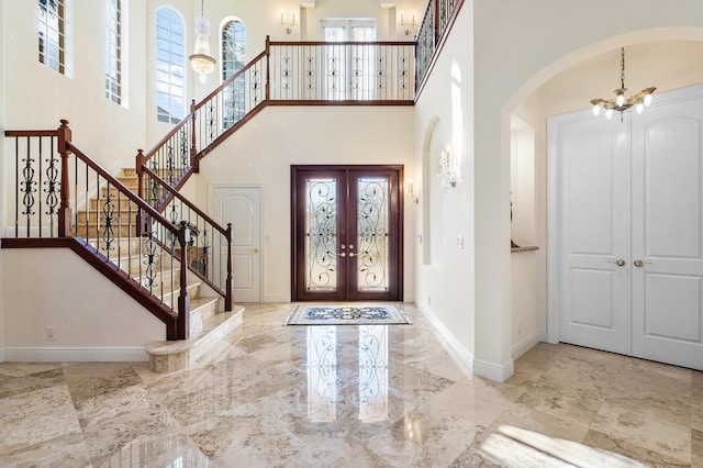 foyer with a high ceiling, french doors, and a chandelier