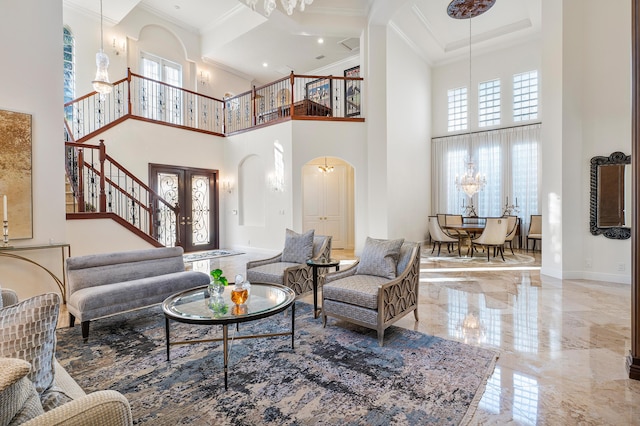 living room with a high ceiling, an inviting chandelier, french doors, and ornamental molding